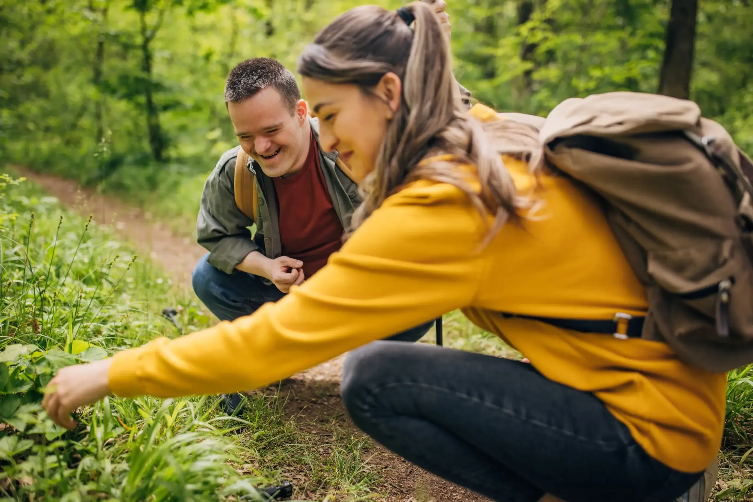 Two friends, a young woman and man with Down syndrom, hiking together in the forest